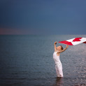 Young boy standing in Gull Lake Alberta holding a Canada Flag in the air above him Strong and Free.