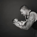 A new dad with arm tattoo holds his newborn daughter in Calgary Alberta.