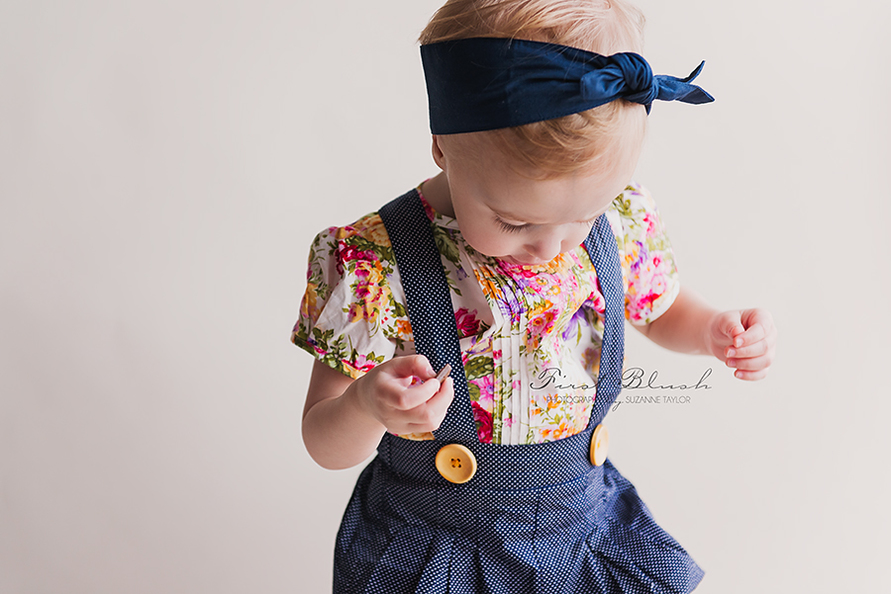 Toddler wearing Lacey Lane jumper and floral blouse with head scarf.