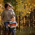 A mom and her toddler son run down a path during a Photography Mini Session in Calgary