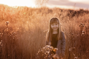 A little girl at sunset smiling at the camera during family photos