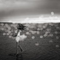 A young girl twirls around in the water looking back at Gull Lake Alberta.